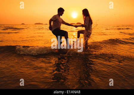 Paare, die Spaß im Meer bei Sonnenuntergang Strand Stockfoto