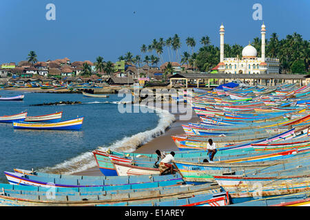 Bunte Fischerboote im Hafen, Mohijedin Palli-Moschee auf der Rückseite, Vizhinjam, Kerala, Indien Stockfoto