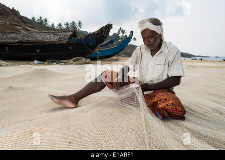 Fischer Reparatur Fischernetze am Strand, Vizhinjam, Kerala, Indien Stockfoto