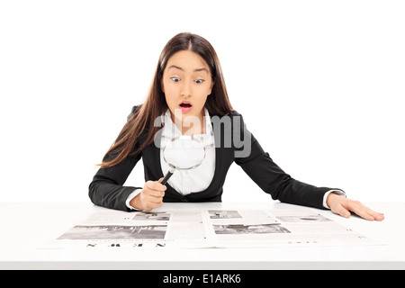 Frau liest die Nachrichten durch ein Vergrößerungsglas Stockfoto