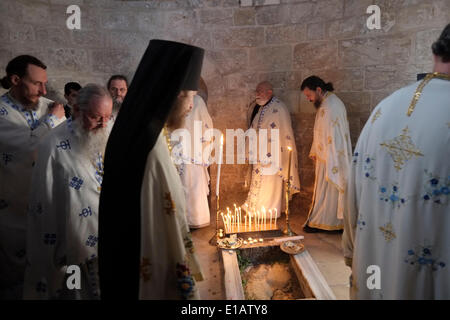 Mitglieder der armenisch-apostolischen Kirche kreisen um eine Steinplatte, von der angenommen wird, dass sie einen der Jesus-Fußabdrücke in der Kapelle der Himmelfahrt enthalten.der Ort, an dem die Gläubigen traditionell glauben, dass er der irdische Ort ist, an dem Jesus nach seiner Auferstehung auf dem Ölberg in den Himmel aufgestiegen ist At-Tur-Distrikt von Ostjerusalem Israel. Jedes Jahr am Donnerstag, dem 40. Tag nach Ostern, feiern Christen auf der ganzen Welt die körperliche Himmelfahrt Jesu in den Himmel. Stockfoto