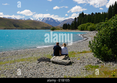 Paar sitzt neben See, Lake Tekapo, Canterbury Region, Südinsel, Neuseeland, Südpazifik Stockfoto