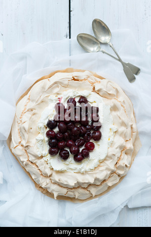 Gebackene Pavlova mit dunklen Kirschen. Stockfoto