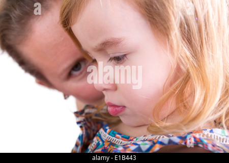 Schützende Mutter wacht über ihre kleine Tochter mit dem hübschen kleinen Mädchen im Profil, um die Kamera mit niedergeschlagenen Augen mit Stockfoto