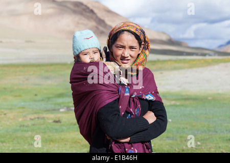 Frau in bunt gemusterten Kopftuch mit Kind im Tragetuch, Region von Tso Kar, Rupshu, Changtang, Ladakh, Indien Stockfoto