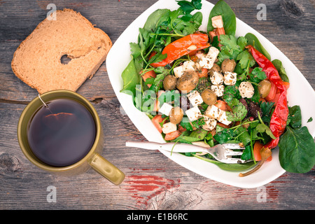 Draufsicht auf eine Schüssel mit leckeren Fisch-grünen grünen Baby-Spinat-Salat mit Brot und Tee auf einer rustikalen Holzoberfläche Stockfoto