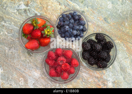 Draufsicht auf eine Auswahl an verschiedenen frischen Beeren im Glas darunter saftige reife Erdbeeren, Brombeeren, blueb Stockfoto