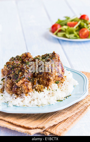 Fried Chicken in Knoblauch-Teriyaki-Sauce bedeckt und bestreut mit Furikake auf einem Bett aus Reis Stockfoto