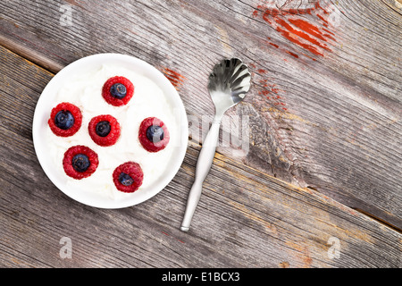 Schüssel mit frischen Himbeeren und Heidelbeeren mit cremigem Joghurt für ein gesundes Frühstück oder tagsüber Snacks, Ansicht von oben auf den Rost Stockfoto