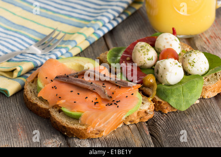 Leckere Sandwiches für ein gesundes Picknick mit Toppings von Avocado, geräuchertem Lachs und Sardellen auf Vollkorn-Brot oder Baby-spi Stockfoto