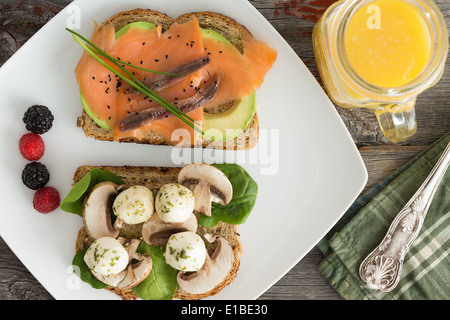 Draufsicht auf einen Teller von gesunden Picknick-Snacks mit frisch gepressten Orangensaft mit zwei belegte Brötchen mit geräuchertem sal Stockfoto