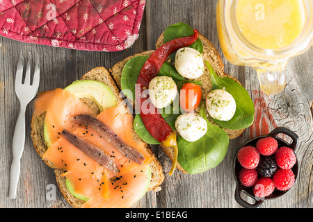 Köstliches Gourmet-belegte Brötchen auf Vollkornbrot belegt mit Räucherlachs, Sardellen, Avocado, Mozzarella, Baby-Spinat ein Stockfoto