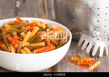 Weiße Keramik Schüssel gefüllt mit bunten Spinat und Tomaten Fusilli italienischen Pasta, hergestellt aus getrockneten Durum-Weizen-Teig und form Stockfoto