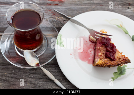 Stück leckere Käsekuchen garniert mit einem Grütze und ein großes Glas frisch gebrühter türkischer Tee gereicht Stockfoto