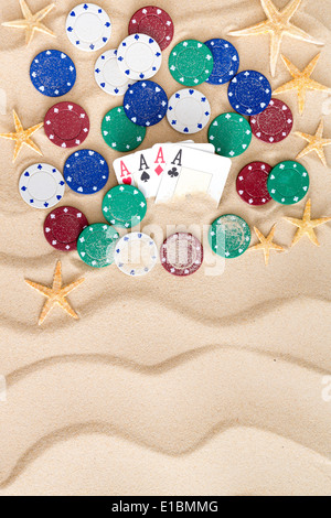 Vier Asse umgeben von Pokerchips und verstreut Seestern am goldenen Sandstrand mit einem dekorativen Wellenmuster und Exemplar Stockfoto