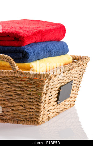 Bunte Stapel von frische saubere Handtücher ordentlich gefaltet in einem Weidenkorb in rot, blau und gelb konzeptionelle an Sauberkeit, hygiene Stockfoto