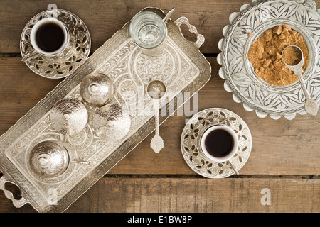 Draufsicht auf ein Tablett mit Cezve zur Beheizung der zerkleinerte oder gemahlenen Kaffeebohnen und zwei Tassen frisch gebrüht traditio Stockfoto