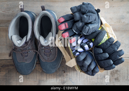 Blick von oben auf ein altes Paar Winter Schnee Stiefel mit einer Tasche voller verschiedene warme Handschuhe und Fäustlinge auf dem Boden einer Kabine Stockfoto