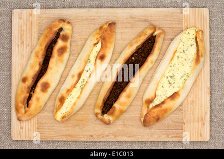 Vier traditionelle türkische Pides, ein ungesäuertes Fladenbrot, garniert mit herzhaften Rindfleisch Hackfleisch und Käse und serviert auf Holz gebacken Stockfoto