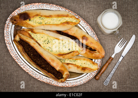 Türkische Pide, einem traditionellen ungesäuertes Fladenbrot mit Hackfleisch und Käse garniert und serviert mit einem Glas Ayran, ein Türkis Stockfoto