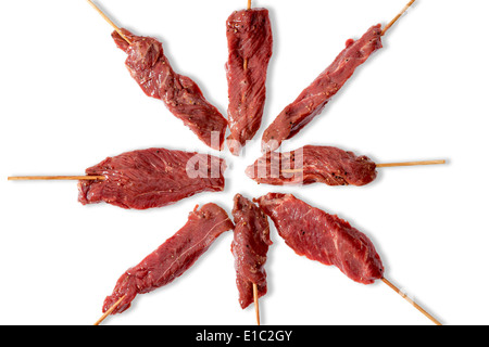 Anordnung der schlanke Ausschreibung roh Rindfleisch Kebab bereit für den Sommer, den Grill auf Stöcken in einem strahlenden Muster auf einem weißen Ba Gewinde Stockfoto