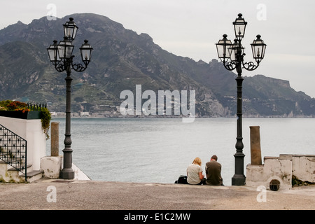 Mann und Frau sitzen auf Stufen in Atrani, mit Blick auf Amalfiküste, Italien Stockfoto