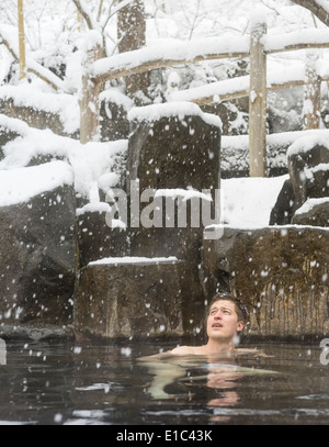 Einweichen in heißem Quellwasser in den Bergen von Japan zu reinigen, im Winterschnee Mann Stockfoto