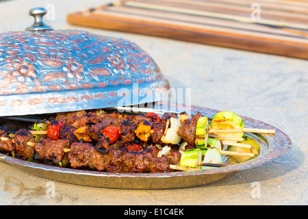 Lecker gegrilltes Rindfleisch und Gemüse Kebab auf Metallplatte mit öffnen gewölbte Deckel auf konkrete Theke in der outdoor-Sommer-Küche Stockfoto