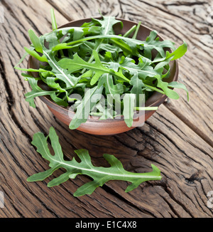 Grüne Rucola Blätter in der Platte auf einem Holztisch. Stockfoto