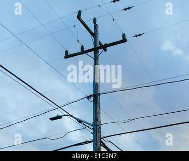 Telefonmast und Stromleitungen von den Boden gegen ein bewölkter Himmel betrachtet. Stockfoto