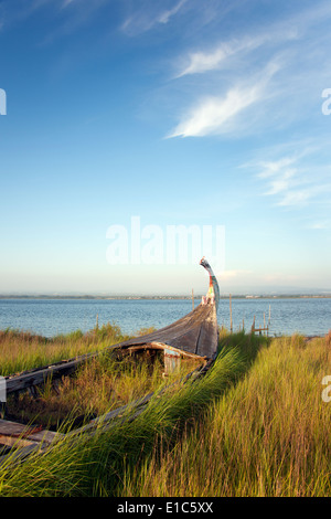 Eine verlassene hölzerne Moliceiros Fischerboot auf den Dünen mit Blick aufs Meer. Stockfoto