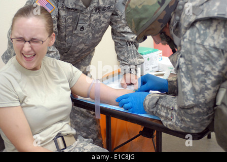 US-Armee Pfc. Natasha Grantham zuckt als Fellow Soldat einen intravenöse Katheter während eines Kampfes Lebensretter verwaltet Stockfoto