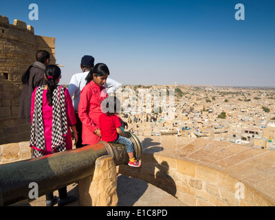 Indien, Rajasthan, Jaisalmer, indische Touristen genießen die Aussicht über Stadt, Fort Bastion, Kind saß auf Kanone Stockfoto