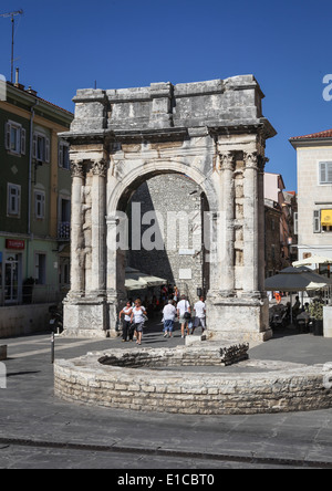 Die Menschen gehen unter alten römischen Triumphbogen genannt den Bogen der Sergier in Pula, Kroatien. Stockfoto