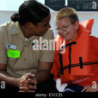 US Navy Yeoman 1. Klasse Datrice Peterson, zugewiesene Flotte Readiness Center Mid-Atlantic, plaudert mit einem Kind an Bord einer Yacht Stockfoto