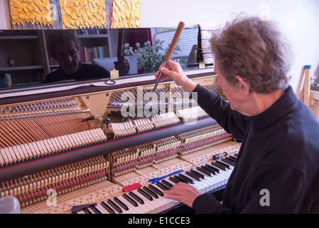 Tuner bei der Arbeit mit Ratsche am Klavier Stockfoto