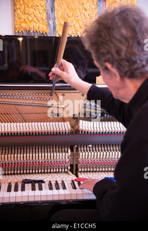 Tuner bei der Arbeit mit Ratsche am Klavier Stockfoto