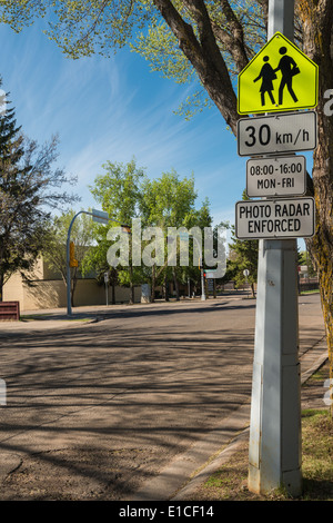 Hinweisschilder Schule zone Geschwindigkeitsbegrenzung mit Schule im Hintergrund, St. Albert, Alberta Stockfoto