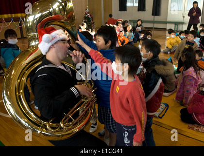 US Navy Musiker 2. Klasse James Brownell, der US 7. Flotte Blasmusik, führt für Kinder während eines Konzerts Urlaub ein Stockfoto