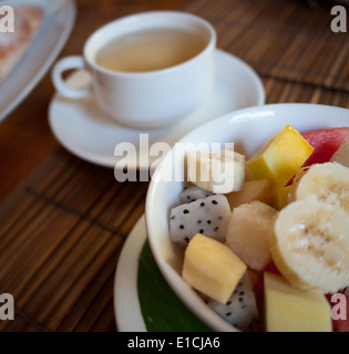 Frühstück mit tropischen Obstsalat (Mango, Dragonfruit, Wassermelone, Banane, Ananas) und Lao geräucherter Grüntee. Stockfoto