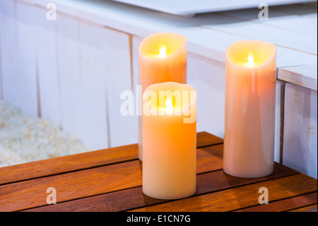 drei brennende Kerzen auf einem Holztisch Stockfoto