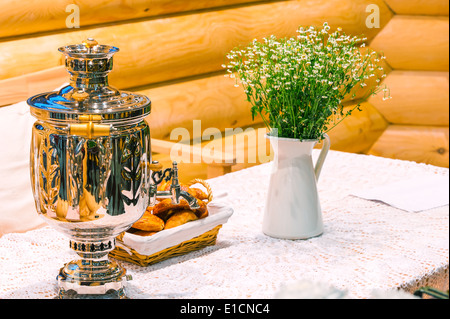 glänzende Samowar und Blumenstrauß auf einem rustikalen Tisch Stockfoto