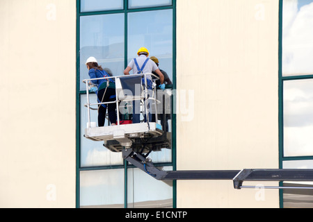 Fensterputzer arbeitet an einer Glasfassade in einer Gondel Stockfoto
