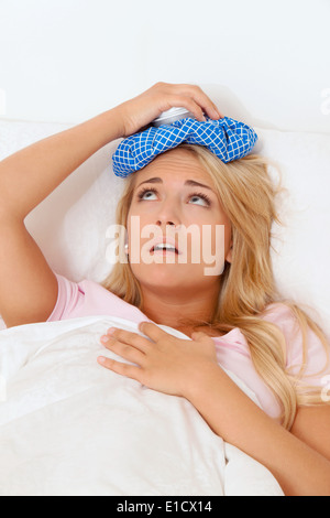 Frau mit Eisbeutel für Kopfschmerzen und Migräne. Heilung mit kalten Kompressen. Stockfoto
