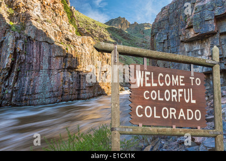 Willkommen im bunten Colorado am Straßenrand Holzschild mit einem Canyon und Whitewater Fluss im Hintergrund Stockfoto