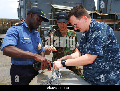 Von rechts, US Navy einem Mate 2. Klasse Cory Clare und Lt. Brandon Le helfen nigerianische Marine Commander Godffrey Kwetishe handeln Stockfoto