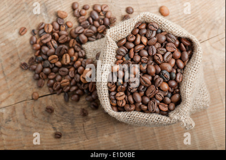 Kaffeebohnen in Jute-Tasche auf Holztisch Stockfoto