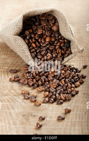 Jute-Tasche mit Kaffeebohnen auf Holztisch Stockfoto