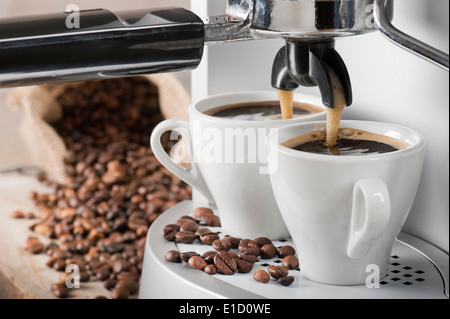 Kaffeemaschine macht zwei Kaffee mit Kaffeebohnen auf Hintergrund Stockfoto