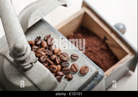 alte Kaffeemühle mit Kaffeebohnen und Kaffeesatz auf Holztisch Stockfoto